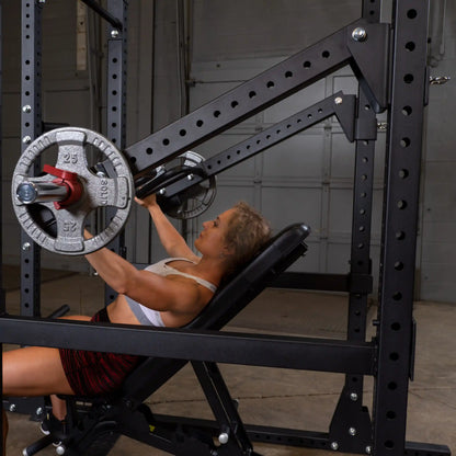 A woman exercising on a Body-Solid Pro Clubline Jammer Arms SPRJAM machine, performing an incline press with weights in a gym setting.