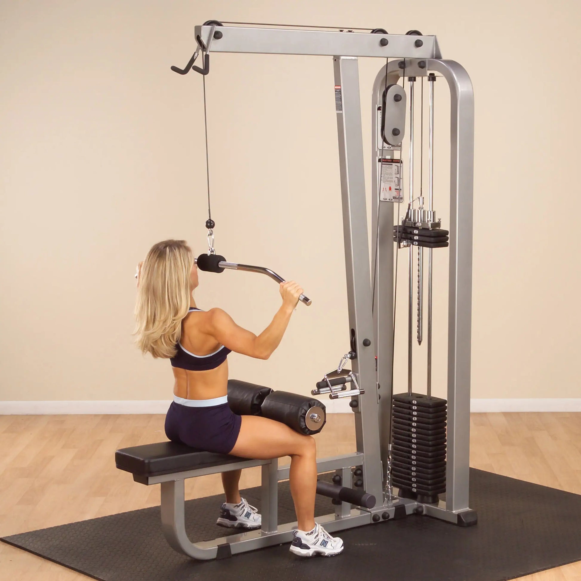 A woman using the Body-Solid Pro Clubline Lat & Mid Row Machine SLM300G2 in a gym setting, performing a rowing exercise.
