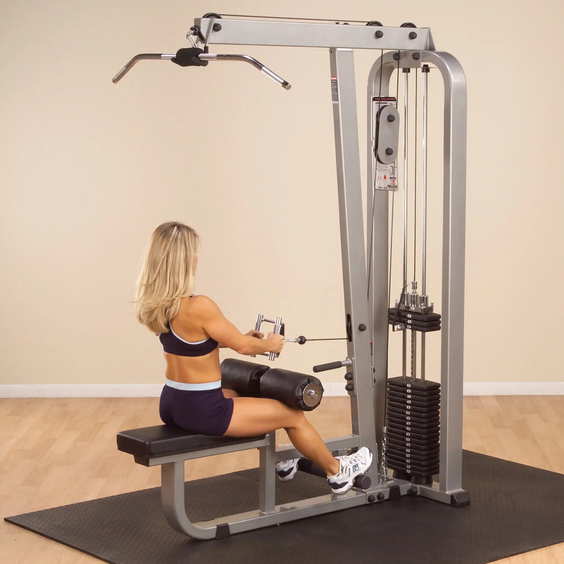 A woman using the Body-Solid Pro Clubline Lat & Mid Row Machine SLM300G2 in a gym setting, performing a rowing exercise.