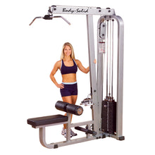 A woman stands next to the Body-Solid Pro Clubline Lat & Mid Row Machine SLM300G2, showcasing its design and features in a gym setting.