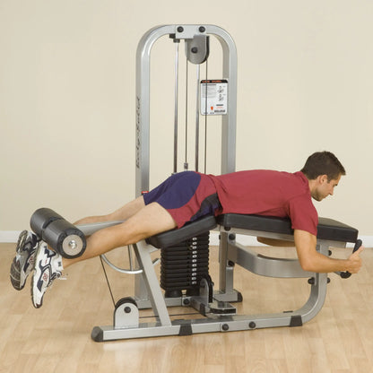 A man using the Body-Solid Pro Clubline Leg Curl Machine SLC400G, performing a leg curl exercise in a gym setting.