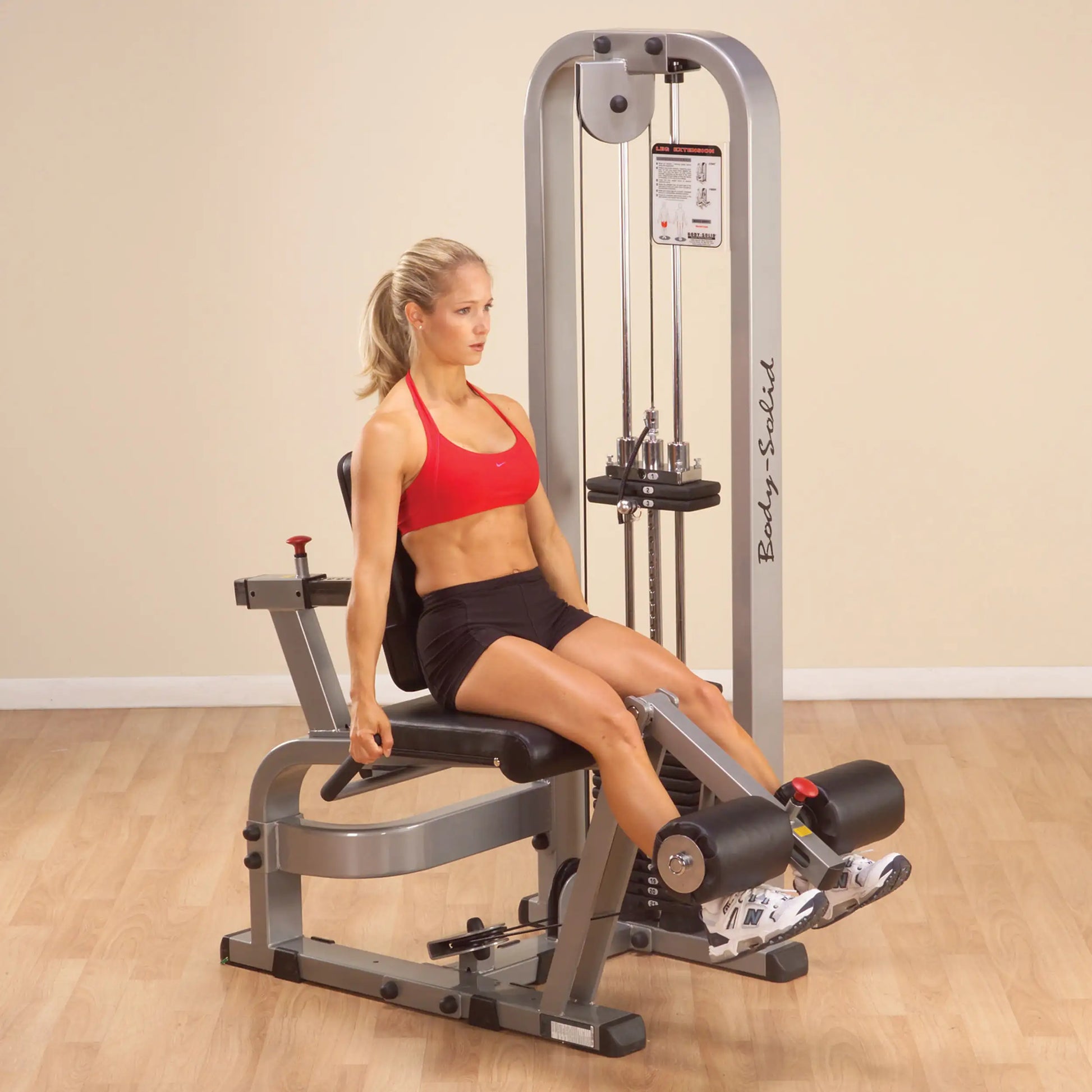 A woman exercising on the Body-Solid Pro Clubline Leg Extension Machine SLE200G2, demonstrating proper form while seated and extending her legs.