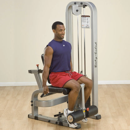 A man using the Body-Solid Pro Clubline Leg Extension Machine SLE200G2 in a gym setting, demonstrating proper exercise form while seated.