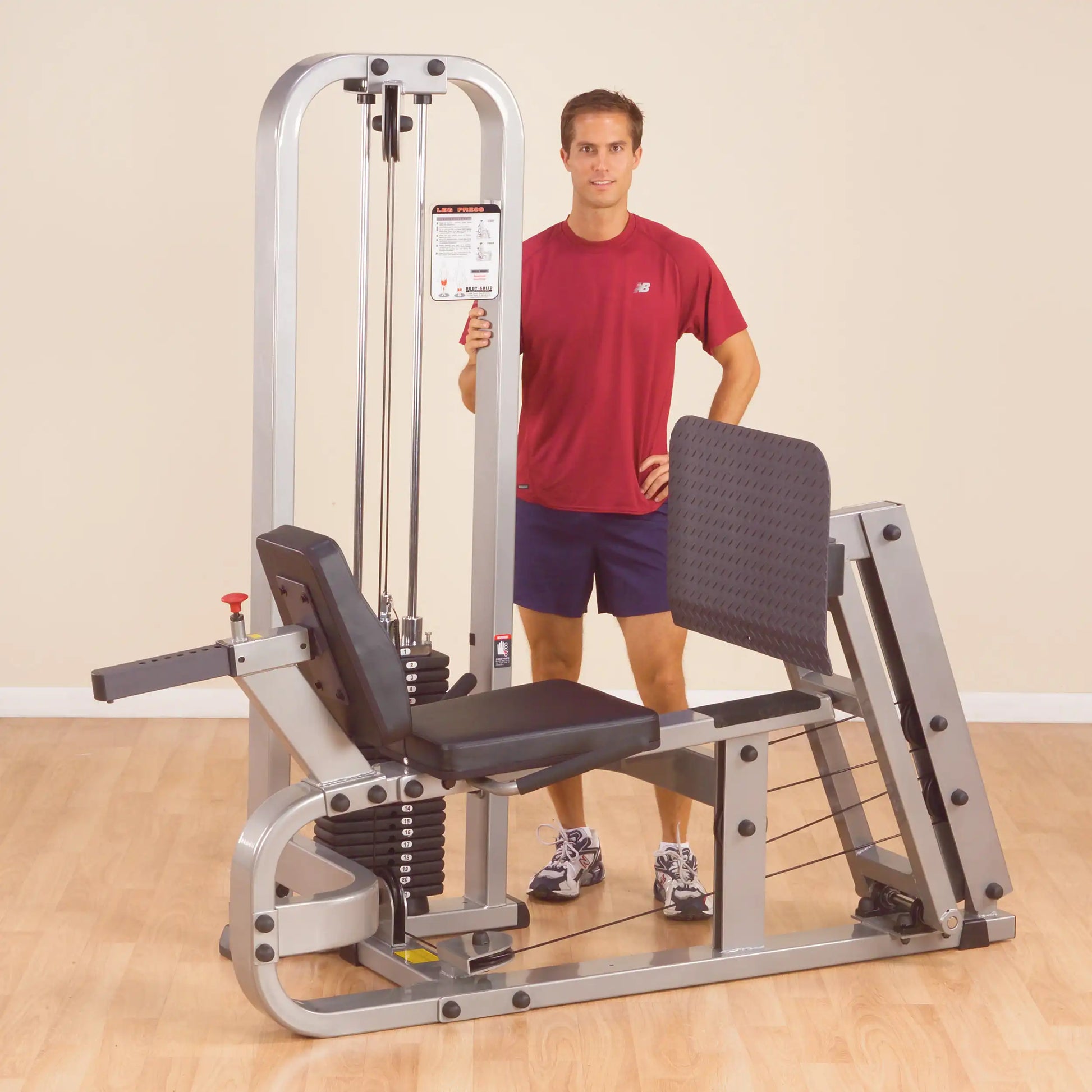 A man standing beside the Body-Solid Pro Clubline Leg Press Machine SLP500G2 in a gym setting, showcasing the machine's design and features.