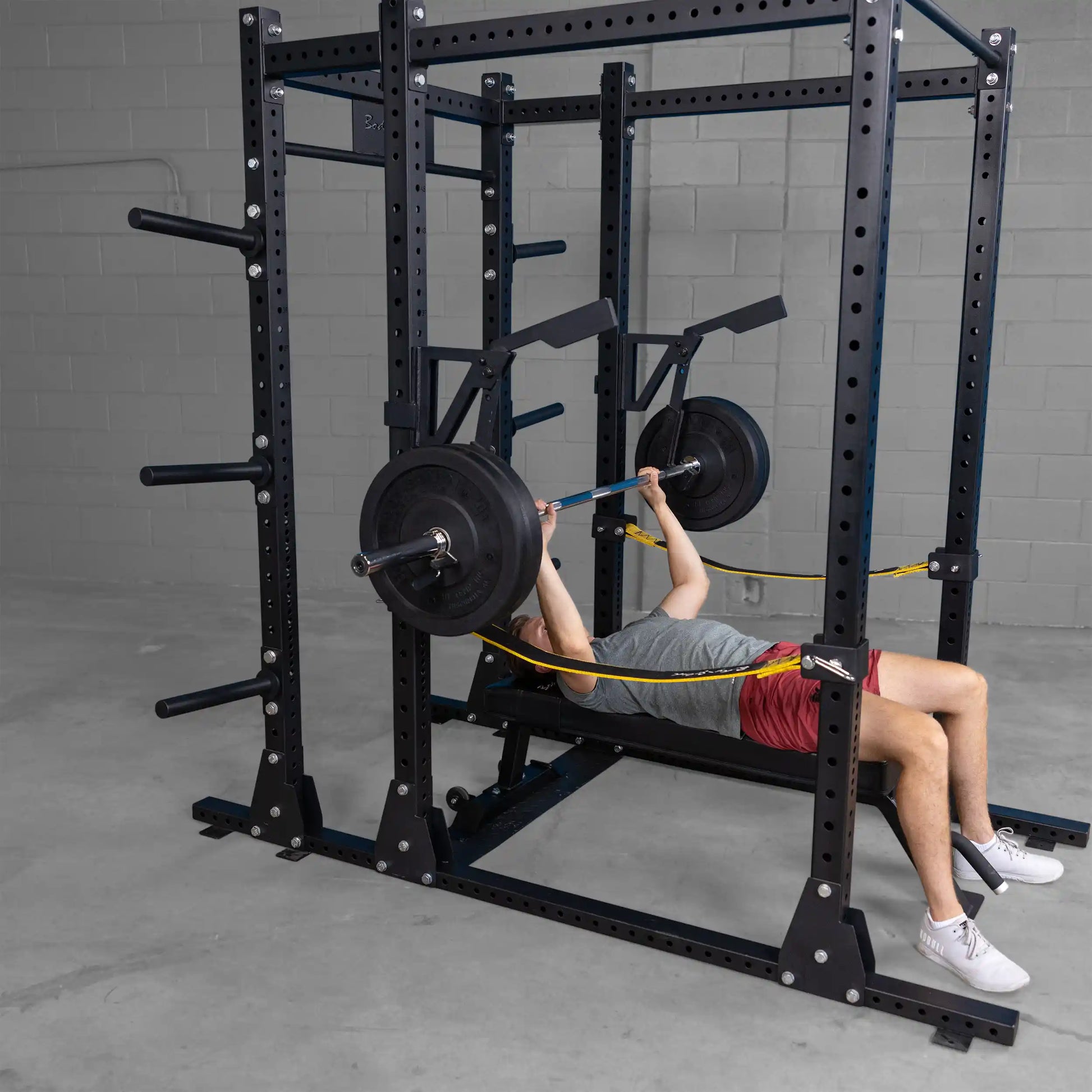 A person performing a bench press using the Body-Solid Pro Clubline Monolift Attachment SPRLFT in a gym setting, showcasing the equipment and exercise.