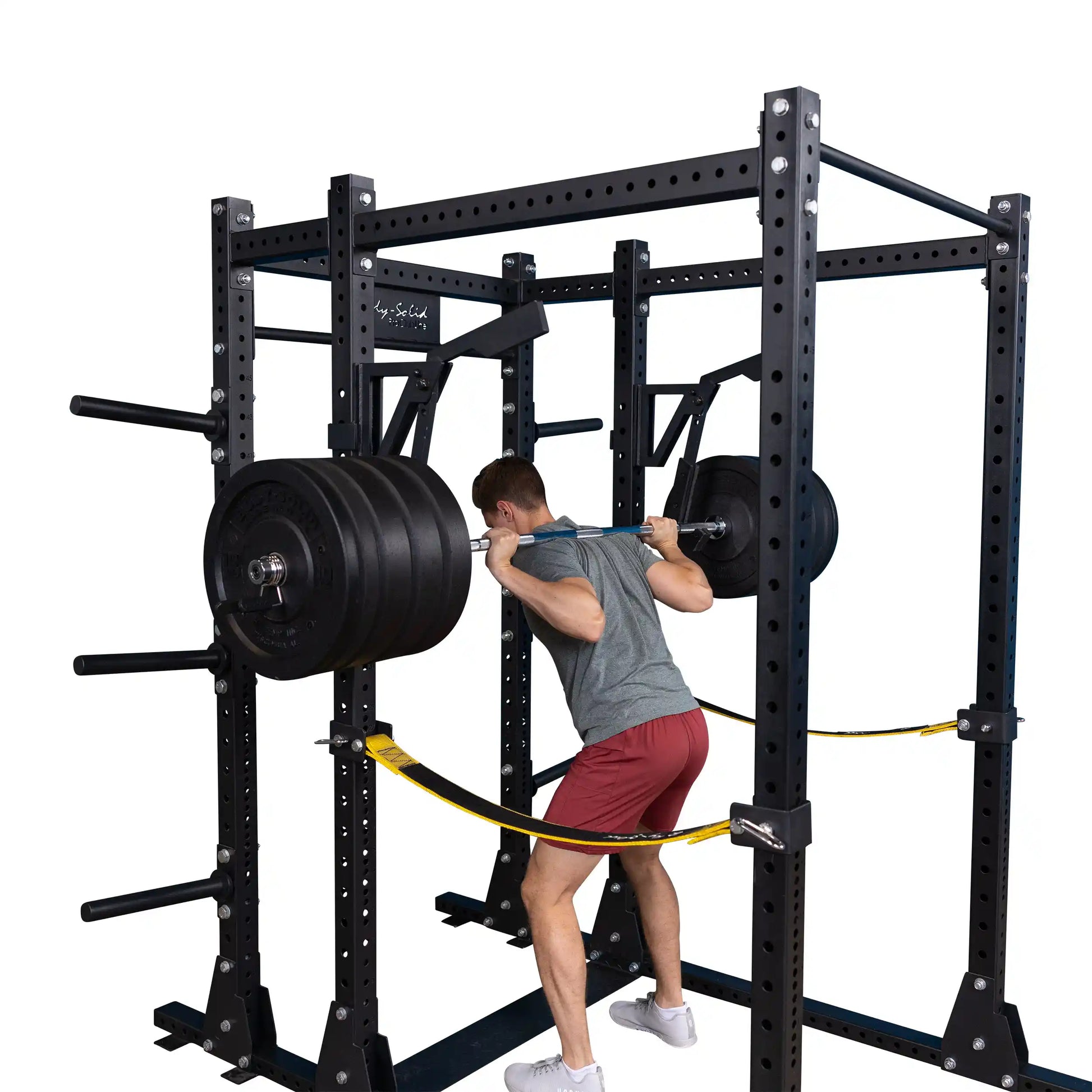 A person performing a squat using the Body-Solid Pro Clubline Monolift Attachment SPRLFT with a barbell and weights on a squat rack.