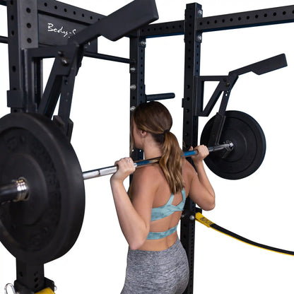 A woman performing a squat with a barbell on a Body-Solid Pro Clubline Monolift Attachment SPRLFT within a strength training setup.