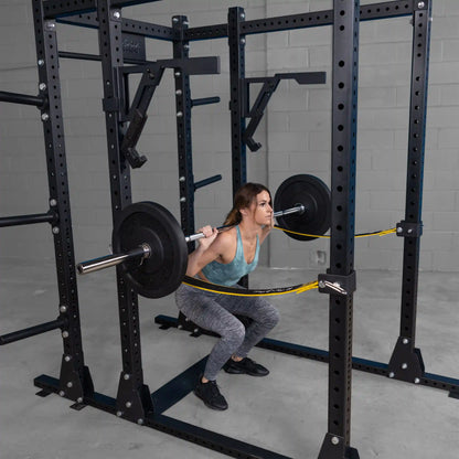 Woman performing squats with a barbell using the Body-Solid Pro Clubline Monolift Attachment SPRLFT in a gym setting, showcasing the equipment's features.
