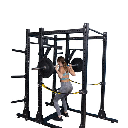 A person performing squats with the Body-Solid Pro Clubline Monolift Attachment SPRLFT, showcasing a squat rack equipped with weight plates and safety straps.