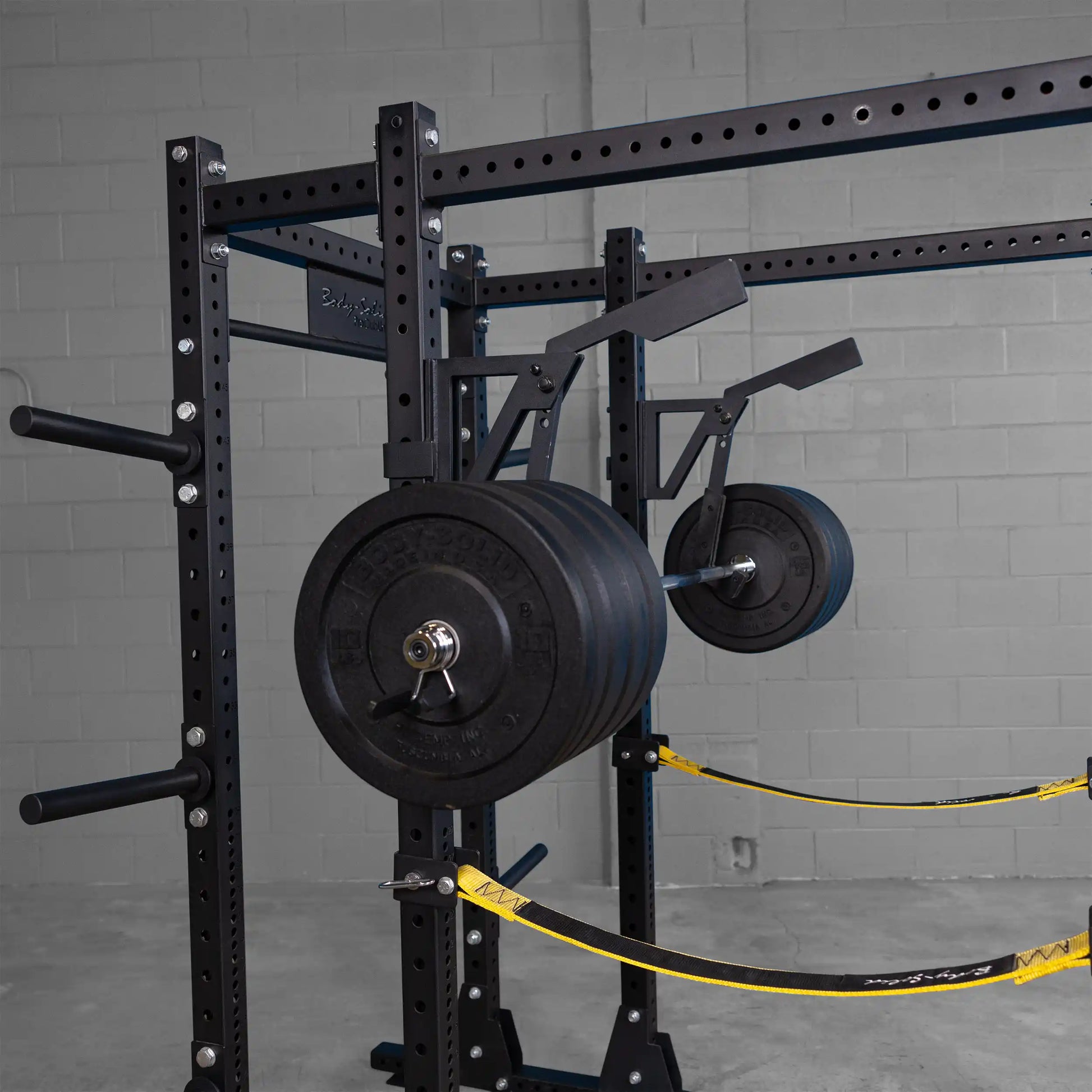 Body-Solid Pro Clubline Monolift Attachment SPRLFT mounted on a weight rack, with heavy black Olympic weight plates, highlighting the sturdy design for strength training.