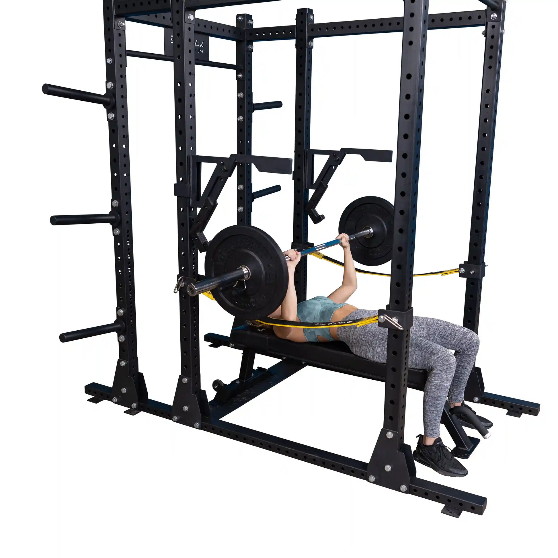 A person performing a bench press with weights using the Body-Solid Pro Clubline Monolift Attachment SPRLFT in a squat rack.