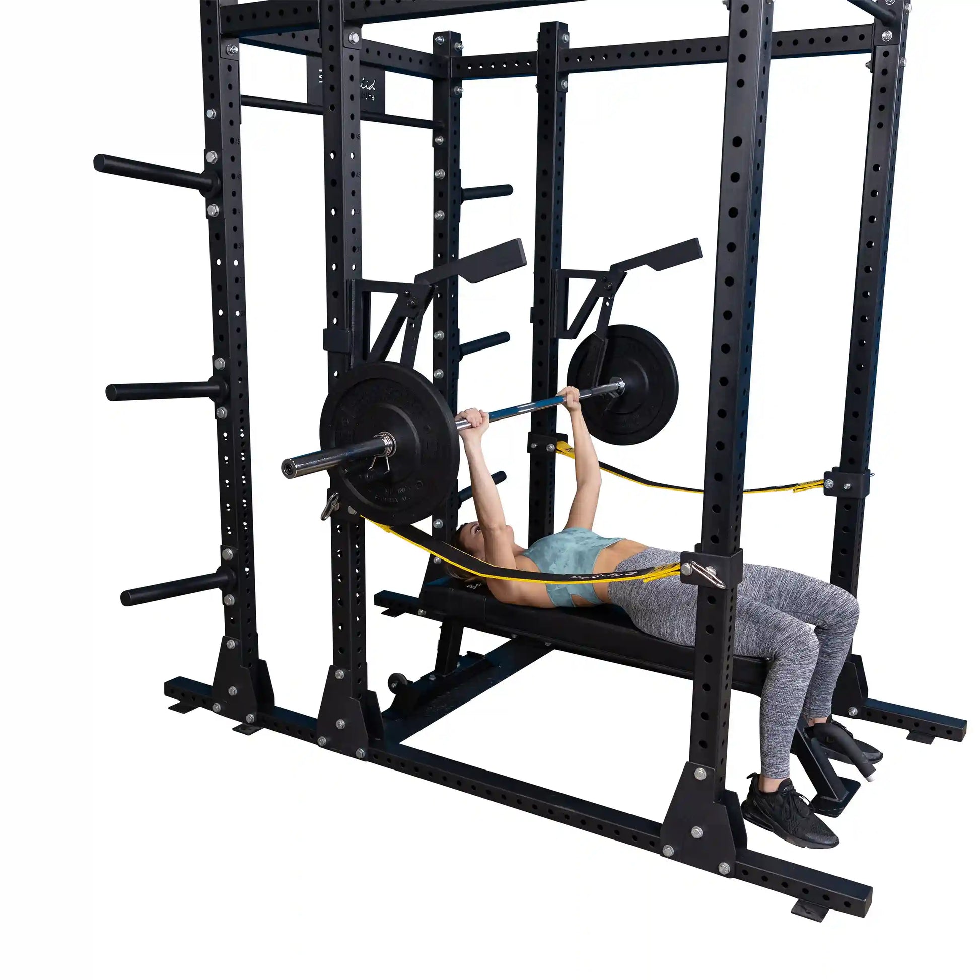 A person performing a bench press using the Body-Solid Pro Clubline Monolift Attachment SPRLFT, showcasing the equipment's sturdy structure and barbell setup in a gym setting.