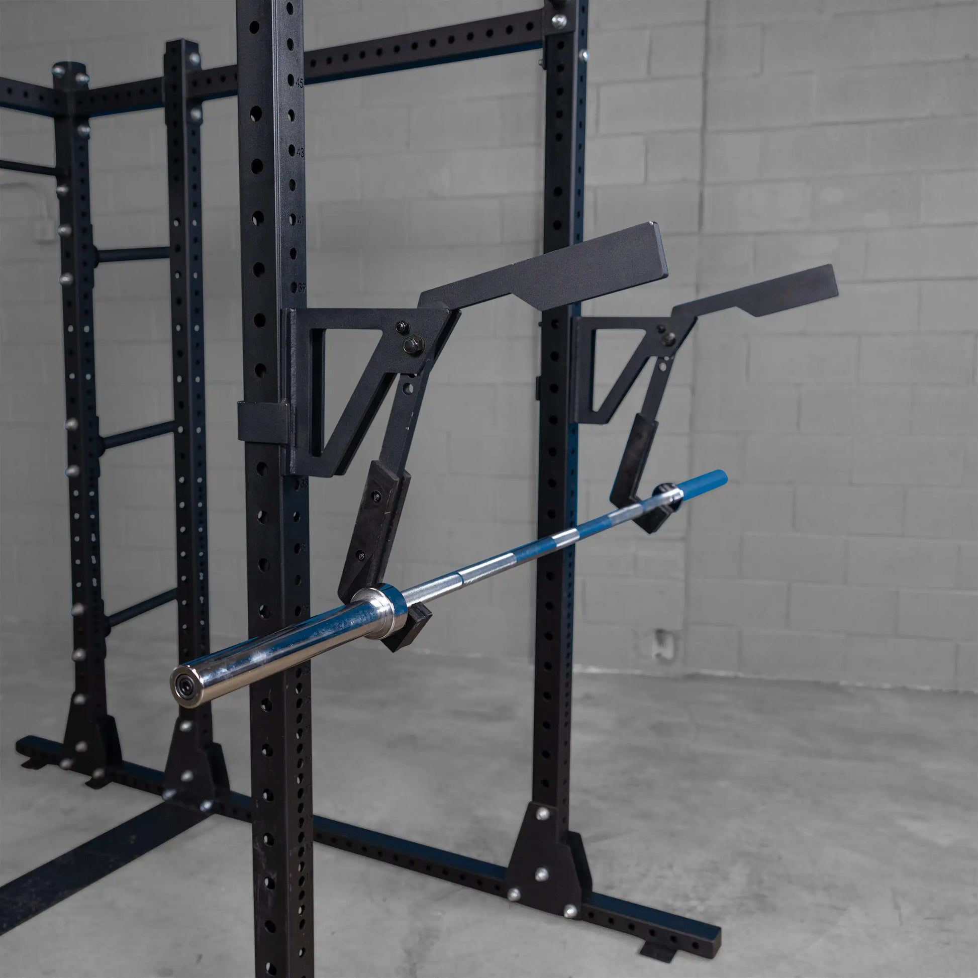 Body-Solid Pro Clubline Monolift Attachment SPRLFT mounted on a squat rack, showcasing a barbell resting securely in place, with a minimalist industrial backdrop.