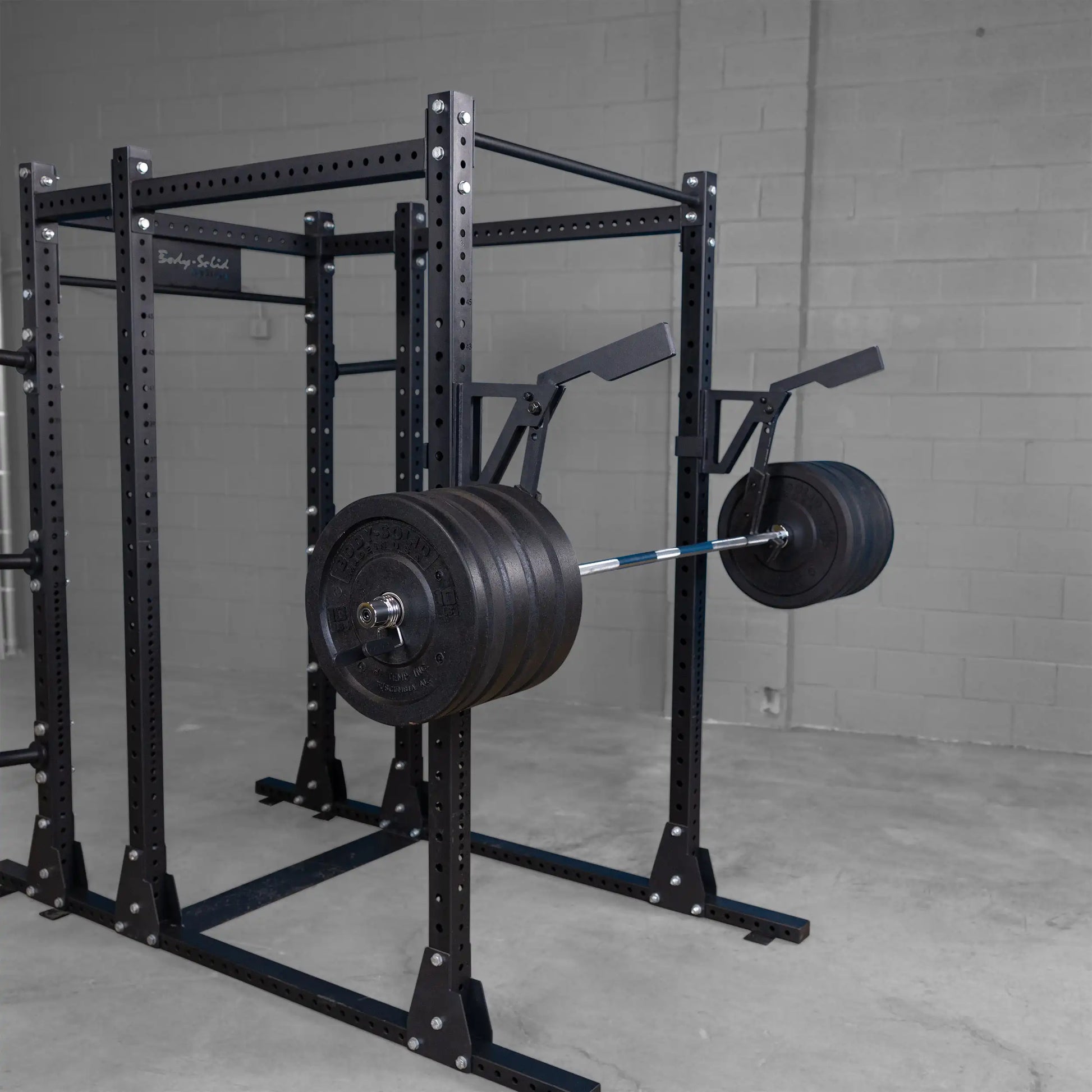Body-Solid Pro Clubline Monolift Attachment SPRLFT mounted on a weightlifting rack, featuring a barbell with heavy weights on either side, set against a gray wall and floor.