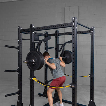 Person using the Body-Solid Pro Clubline Monolift Attachment SPRLFT for squats inside a weightlifting rack, with weights loaded on the barbell.