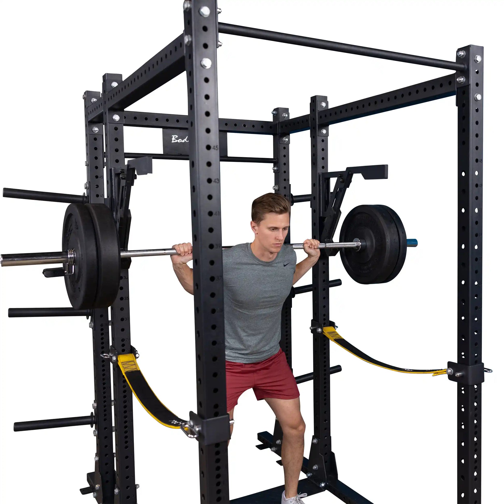 A person performing squats with a barbell in a weightlifting frame featuring the Body-Solid Pro Clubline Monolift Attachment SPRLFT.