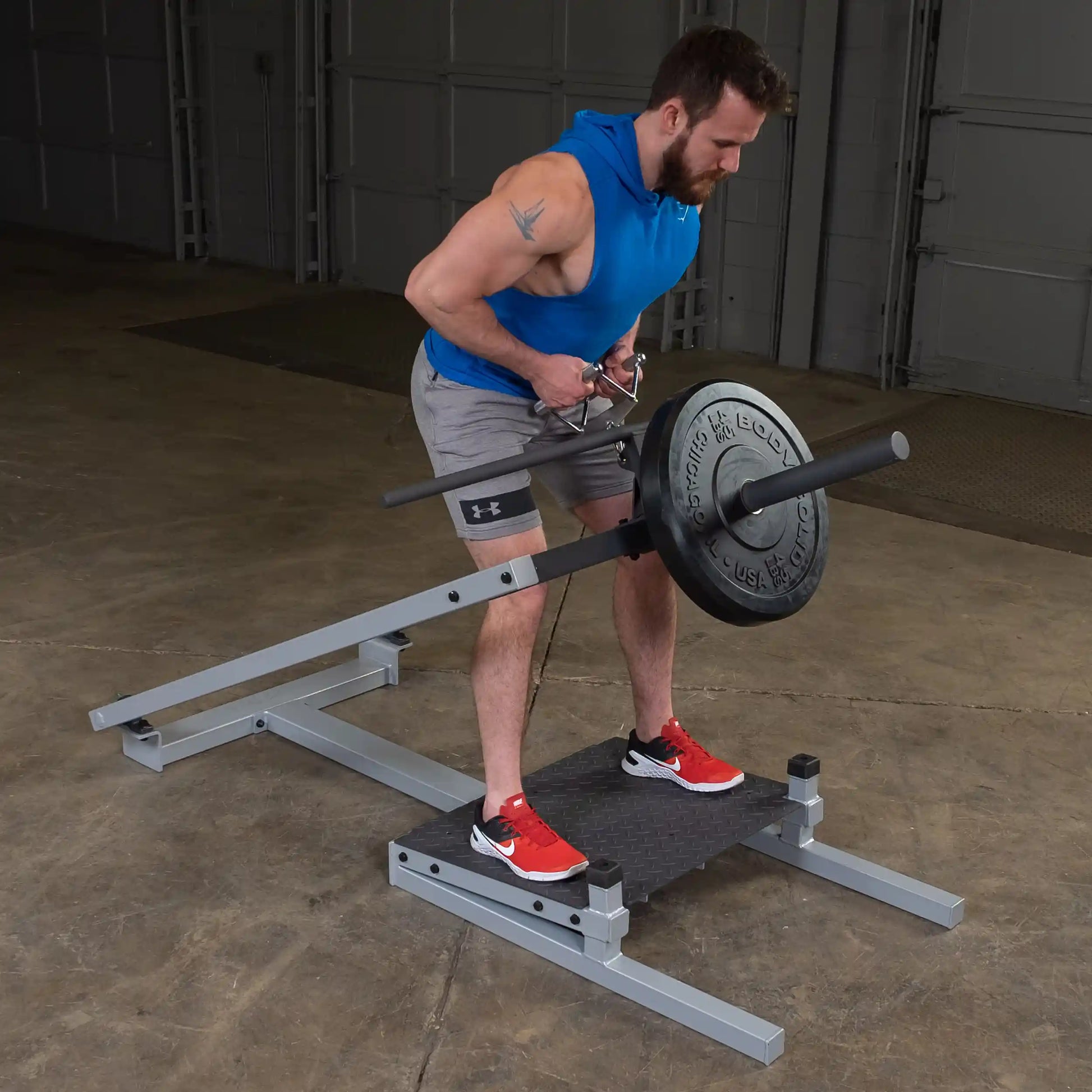 A person using the Body-Solid Pro Clubline T-Bar Row Machine STBR500, performing a rowing exercise with weights in a gym setting.
