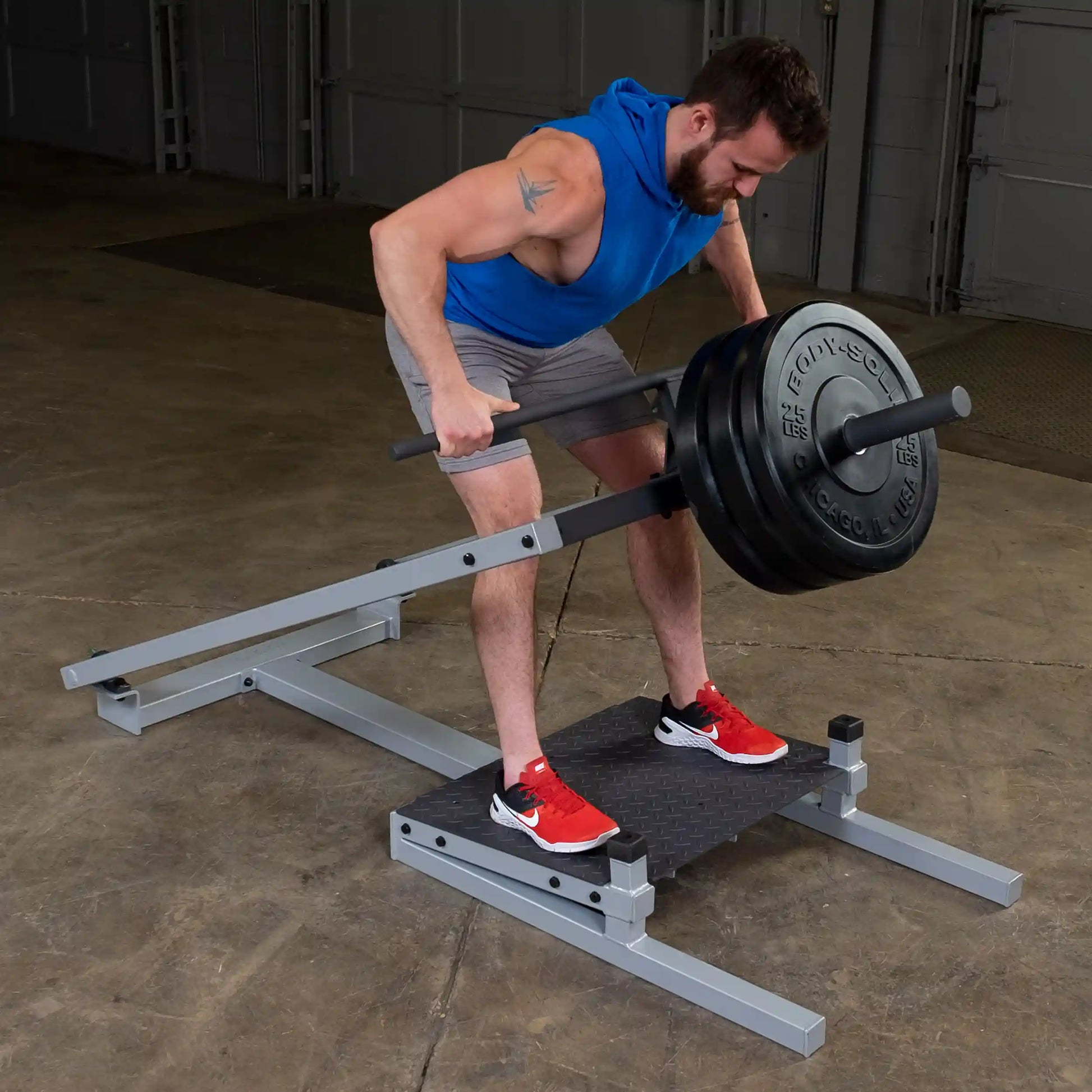 A person demonstrating the Body-Solid Pro Clubline T-Bar Row Machine STBR500, performing a T-bar row exercise with weights, in a gym setting.