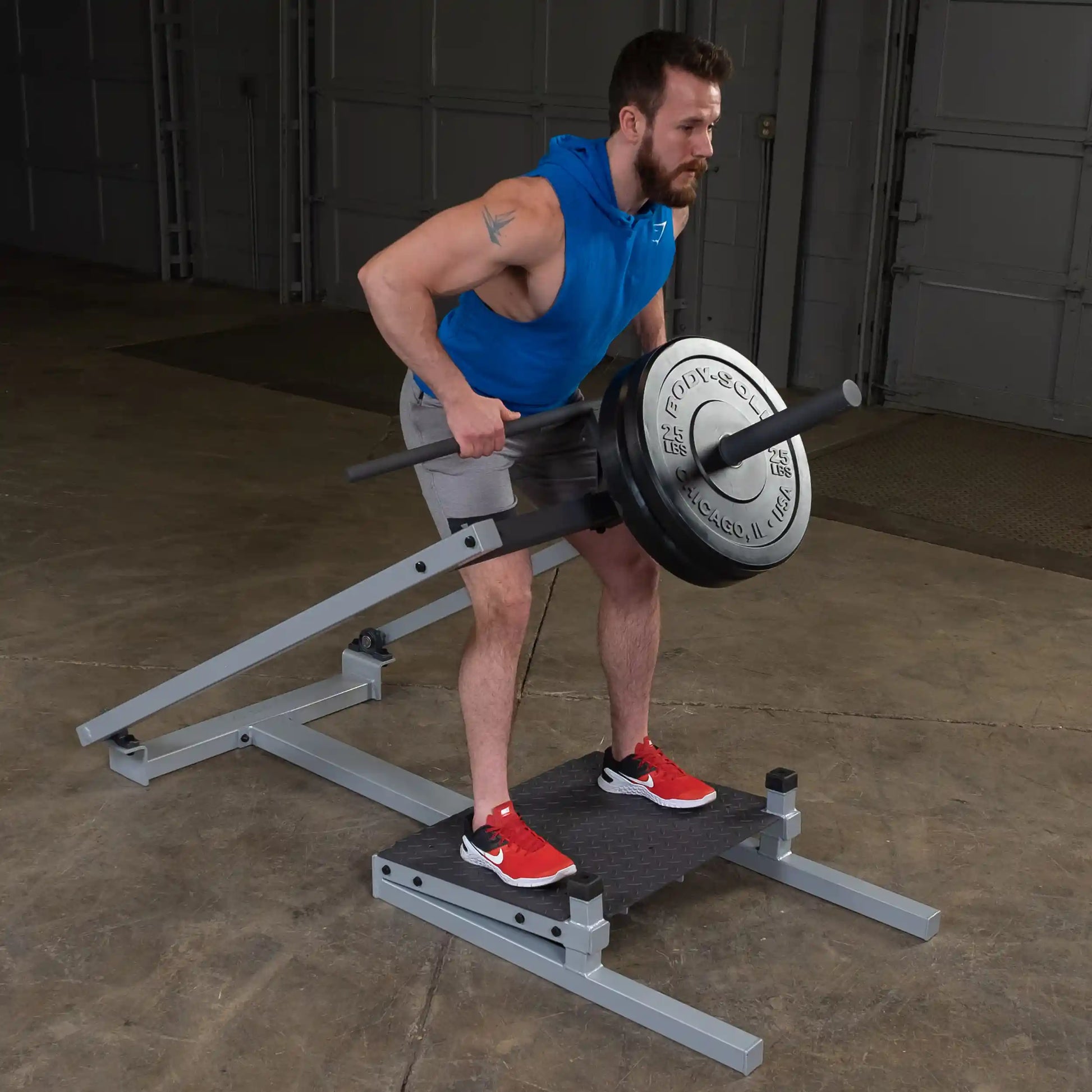 A man using the Body-Solid Pro Clubline T-Bar Row Machine STBR500, performing a bent-over row exercise in a gym setting.