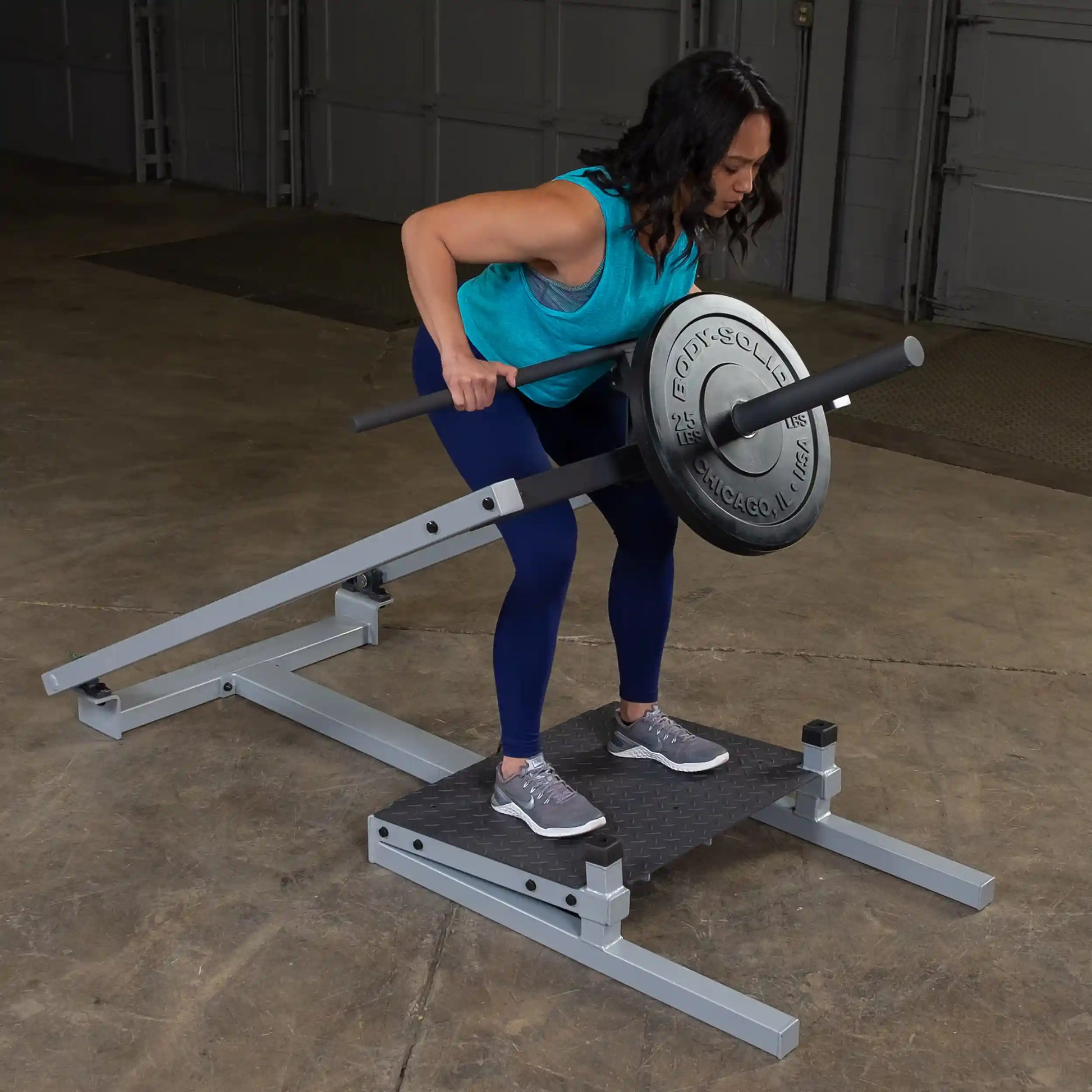 A woman performing a bent-over row exercise on a Body-Solid Pro Clubline T-Bar Row Machine STBR500 in a gym setting.