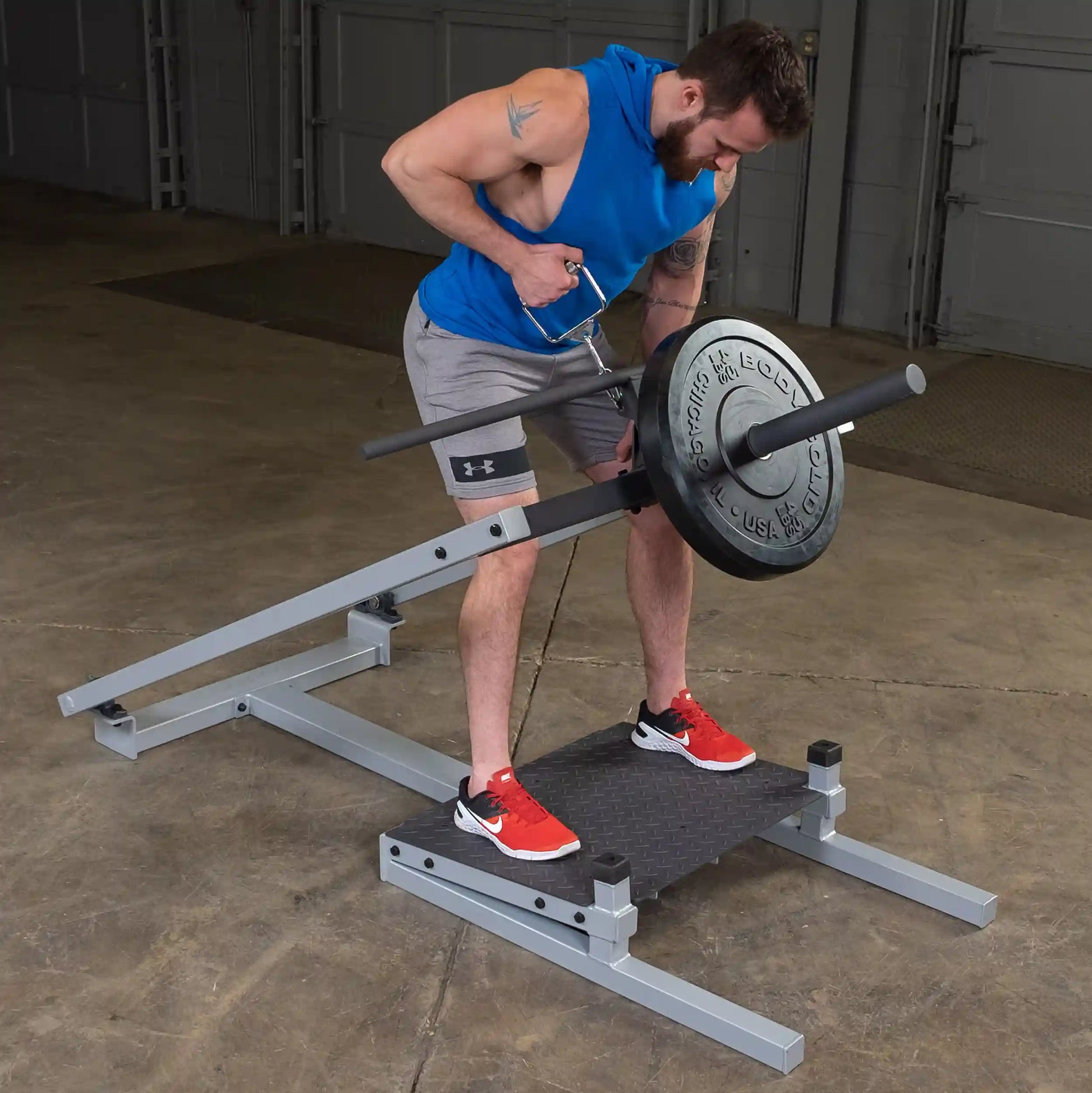 A person using the Body-Solid Pro Clubline T-Bar Row Machine STBR500, performing a rowing exercise with a weight plate attached, in a gym setting.