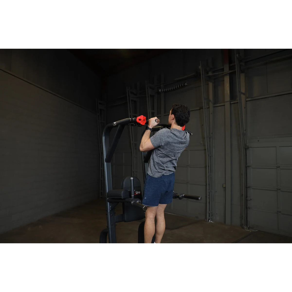 Person using the Body-Solid Pro Clubline Vertical Knee Raise SVKR1000 in a gym setting, demonstrating an exercise.