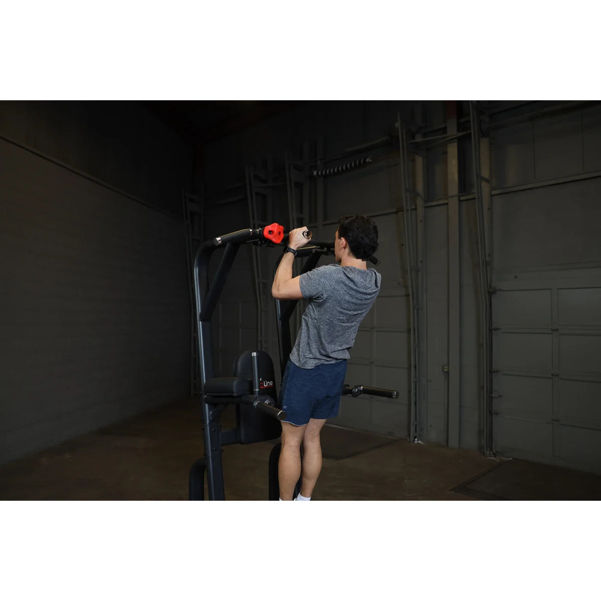 A person using the Body-Solid Pro Clubline Vertical Knee Raise SVKR1000 for an exercise in a gym setting.