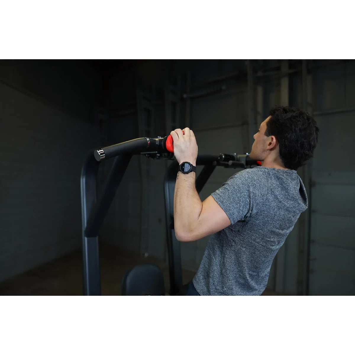 A person using the Body-Solid Pro Clubline Vertical Knee Raise SVKR1000, performing a knee raise exercise while gripping the handles.