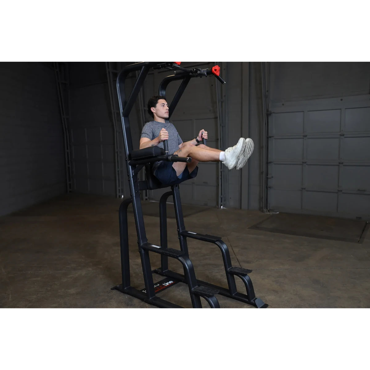 A person using the Body-Solid Pro Clubline Vertical Knee Raise SVKR1000 exercise machine, performing knee raises in a gym setting.