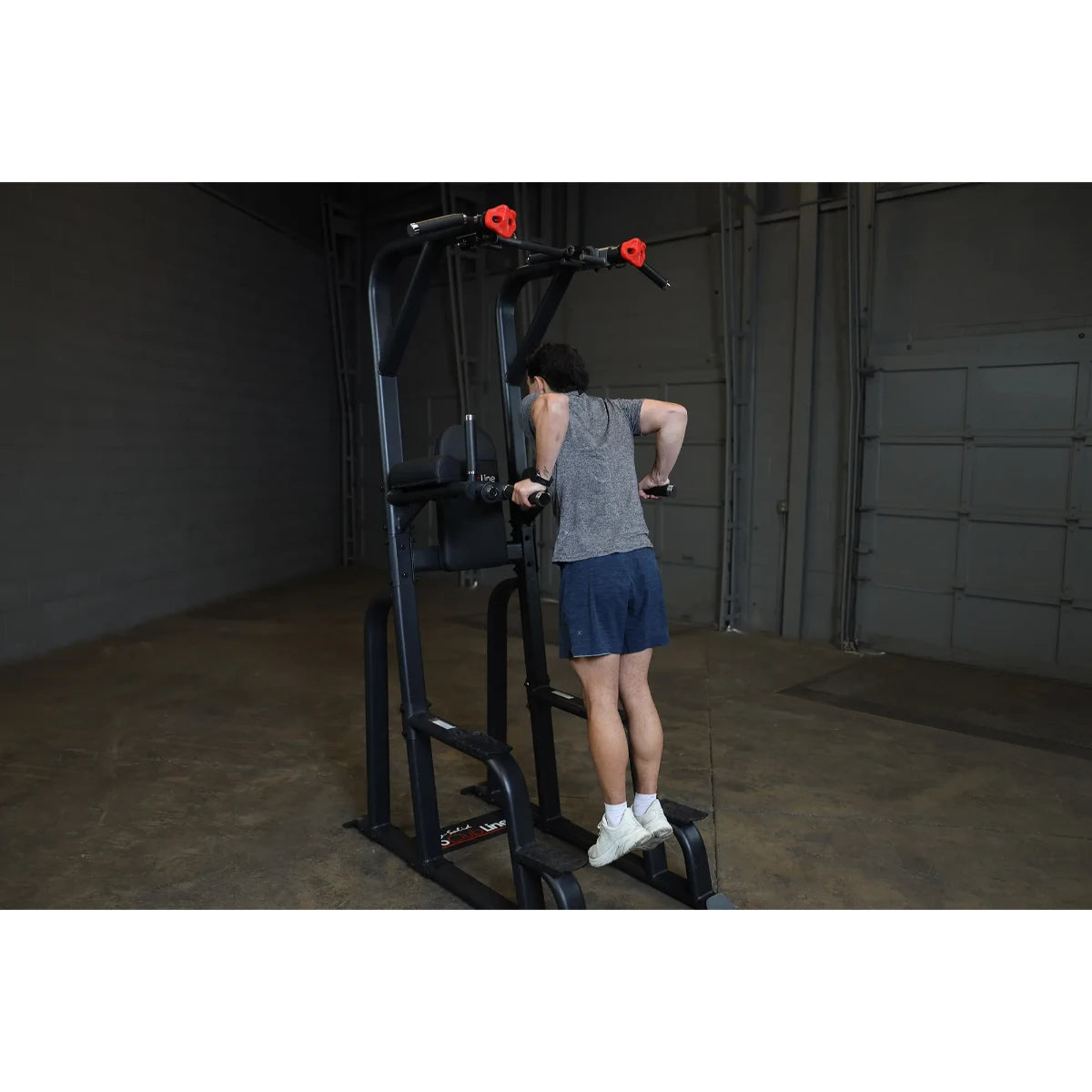 A person using the Body-Solid Pro Clubline Vertical Knee Raise SVKR1000 for an exercise routine in a gym setting.