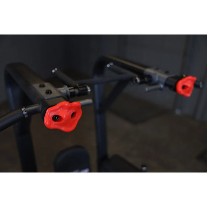 Close-up view of the handles on the Body-Solid Pro Clubline Vertical Knee Raise SVKR1000, featuring red grips and a sturdy design for effective workout support.