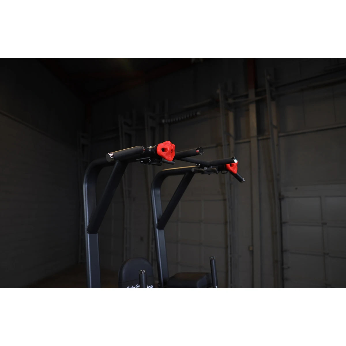 Close-up view of the Body-Solid Pro Clubline Vertical Knee Raise SVKR1000, showcasing its padded handles and frame design against a dark background.