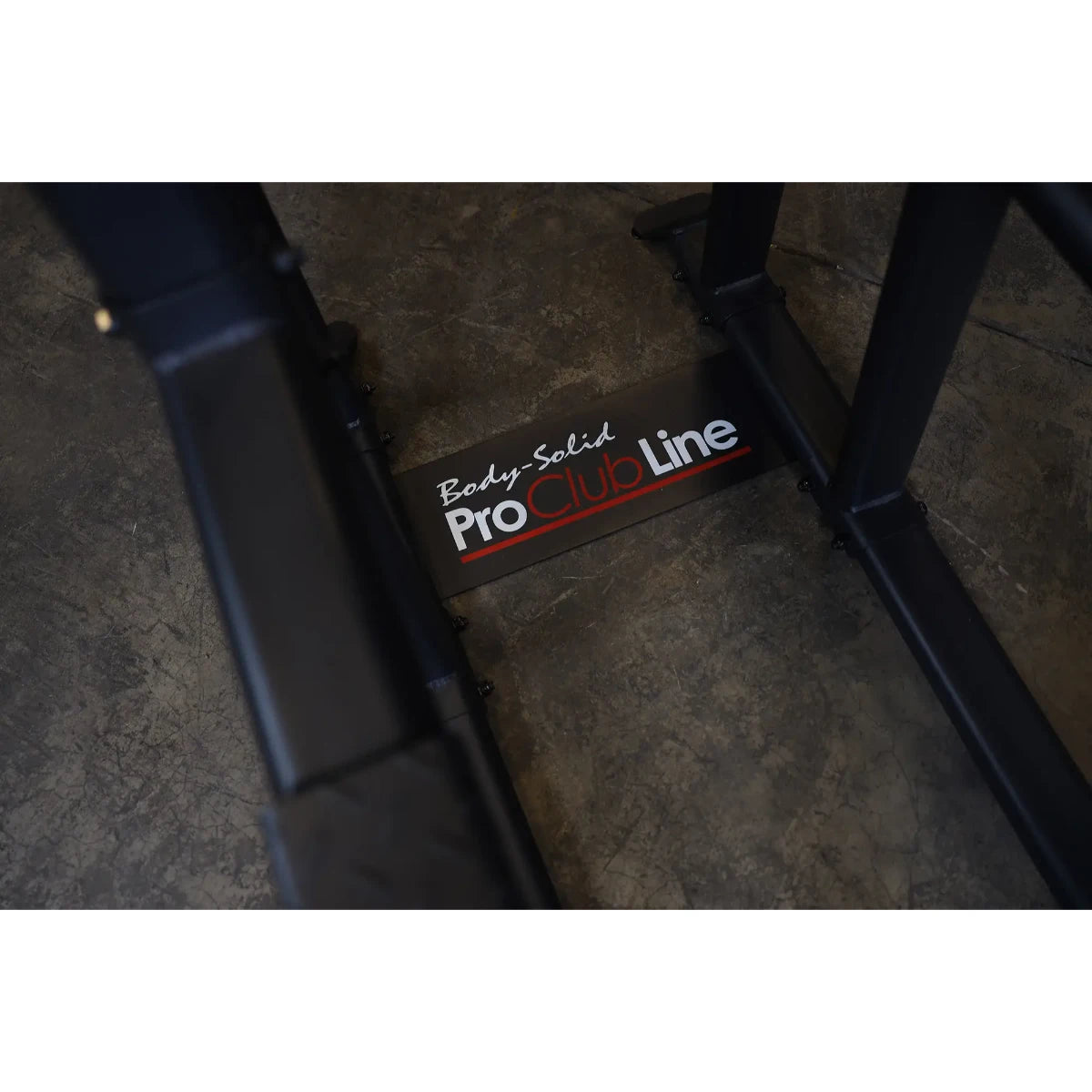 Close-up view of the Body-Solid Pro Clubline Vertical Knee Raise SVKR1000 logo on the equipment's base, set against a textured floor.