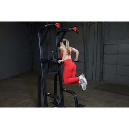 A person performing an exercise on the Body-Solid Pro Clubline Vertical Knee Raise SVKR1000, demonstrating proper form while using the equipment in a gym setting.