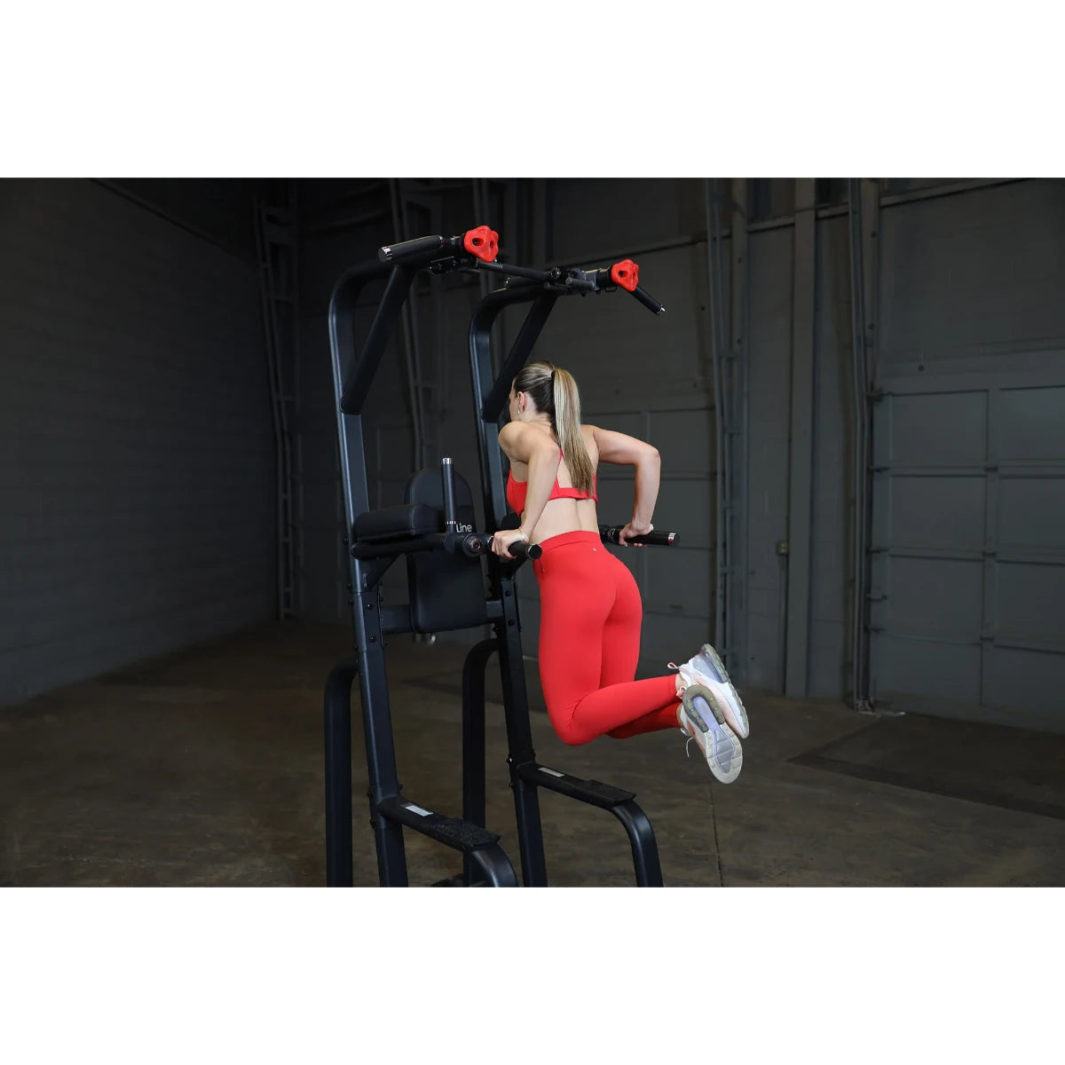 A person using the Body-Solid Pro Clubline Vertical Knee Raise SVKR1000, performing a knee raise exercise in a gym setting.