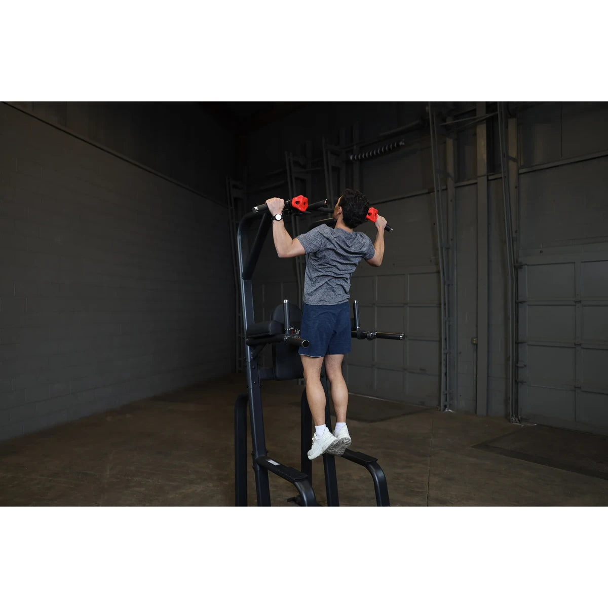 A person performing an exercise on the Body-Solid Pro Clubline Vertical Knee Raise SVKR1000 in a gym setting.