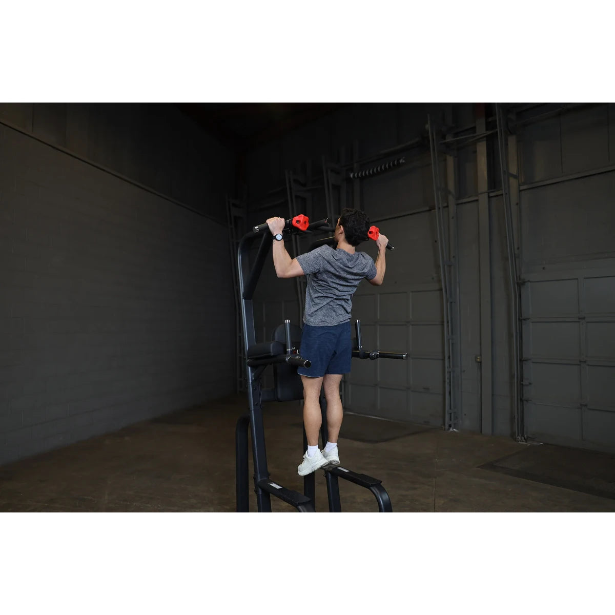 A person using the Body-Solid Pro Clubline Vertical Knee Raise SVKR1000 in a gym setting, performing a knee raise exercise.