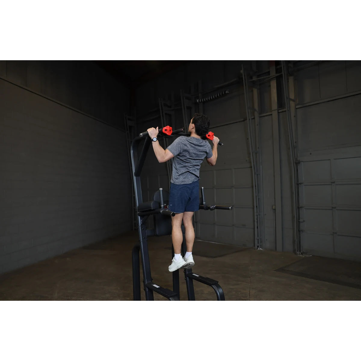 A person performing an exercise on the Body-Solid Pro Clubline Vertical Knee Raise SVKR1000 in a gym setting.