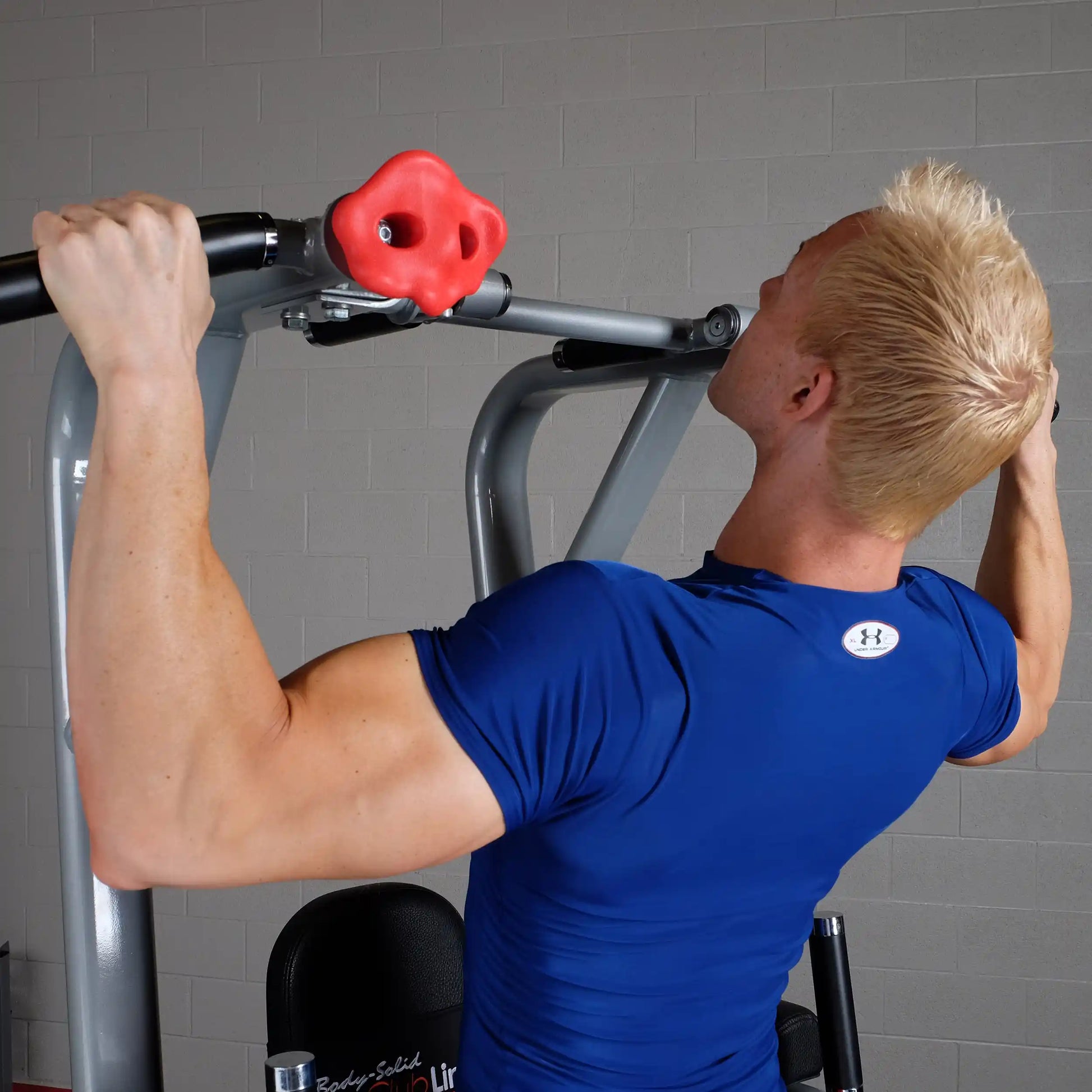 A person using the Body-Solid Pro Clubline Vertical Knee Raise SVKR1000 machine, performing an exercise with a focus on upper body strength.
