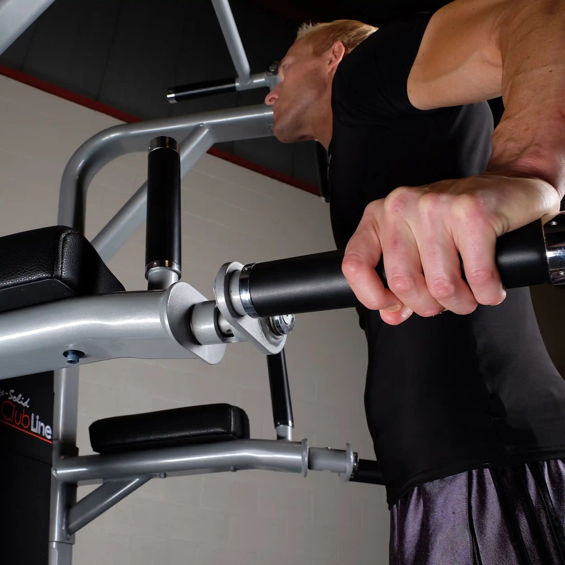Close-up of a person using the Body-Solid Pro Clubline Vertical Knee Raise SVKR1000, focusing on their hands gripping the handles.
