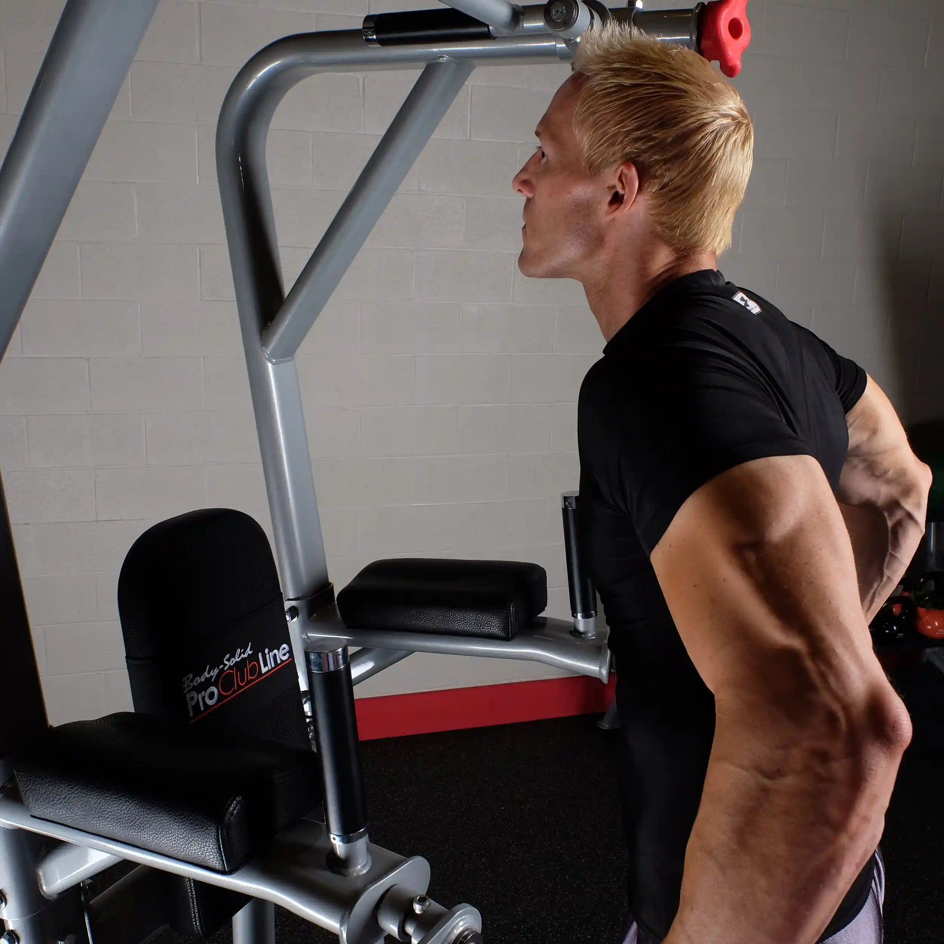 A person using the Body-Solid Pro Clubline Vertical Knee Raise SVKR1000 exercise machine, focusing on their form while performing an exercise.