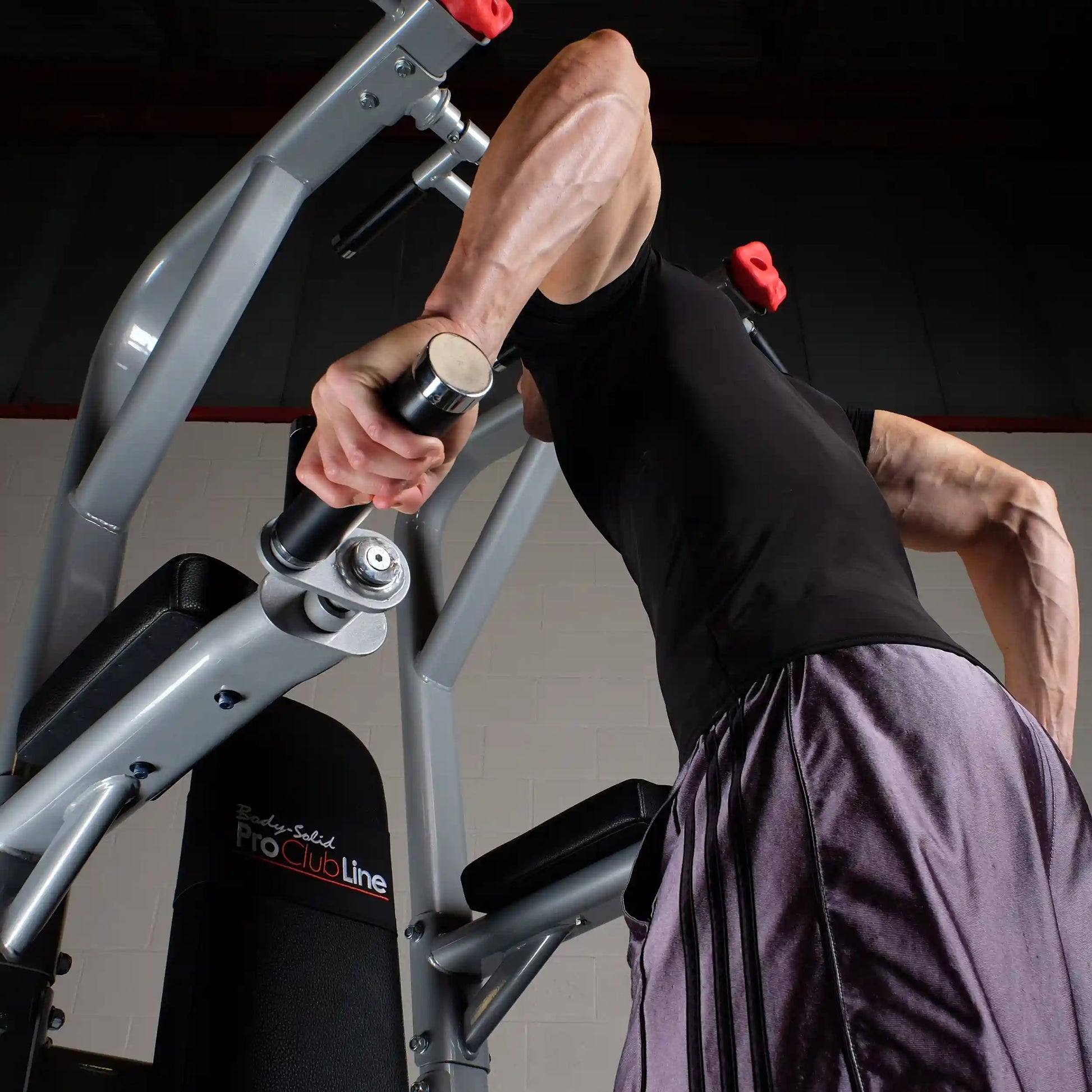A person using the Body-Solid Pro Clubline Vertical Knee Raise SVKR1000, demonstrating strength training with a focus on their upper body.
