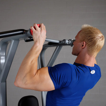A person using the Body-Solid Pro Clubline Vertical Knee Raise SVKR1000, performing an exercise with a focused expression in a gym setting.