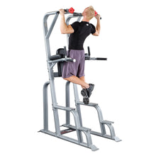 A person performing an exercise on the Body-Solid Pro Clubline Vertical Knee Raise SVKR1000, using the pull-up and knee raise features of the equipment.