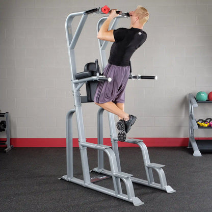 A person demonstrating an exercise on the Body-Solid Pro Clubline Vertical Knee Raise SVKR1000, performing a pull-up with feet elevated, in a gym setting.