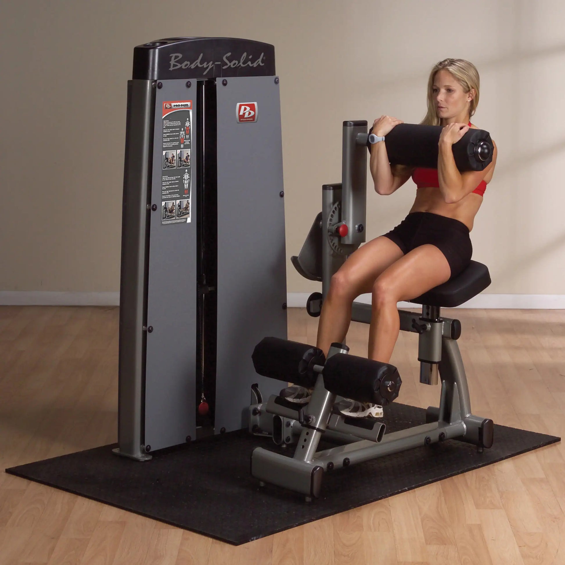A woman using the Body-Solid Pro Dual Ab & Back Machine DABBSF in a gym setting, demonstrating an abdominal exercise with a weight bar.