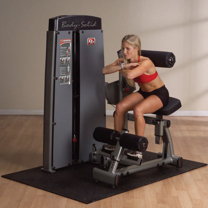 A woman using the Body-Solid Pro Dual Ab & Back Machine DABBSF in a gym setting, demonstrating an abdominal exercise.