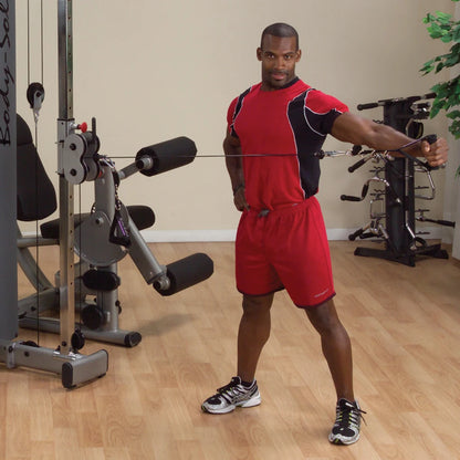 A man in a red workout outfit demonstrating an exercise on the Body-Solid Pro Dual Cable Column Machine DPCCSF in a gym setting.