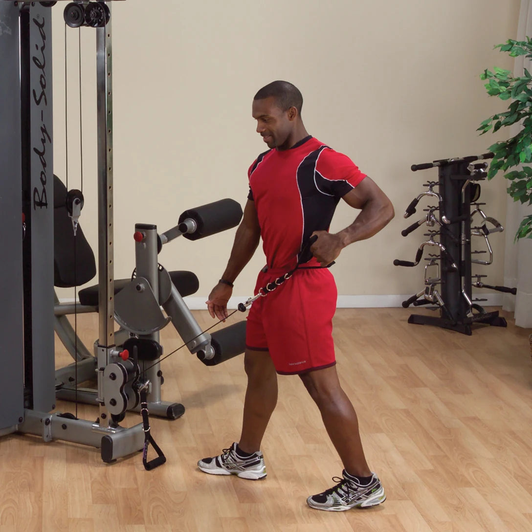 A man exercising with the Body-Solid Pro Dual Cable Column Machine DPCCSF, performing a cable workout in a bright, spacious gym environment.