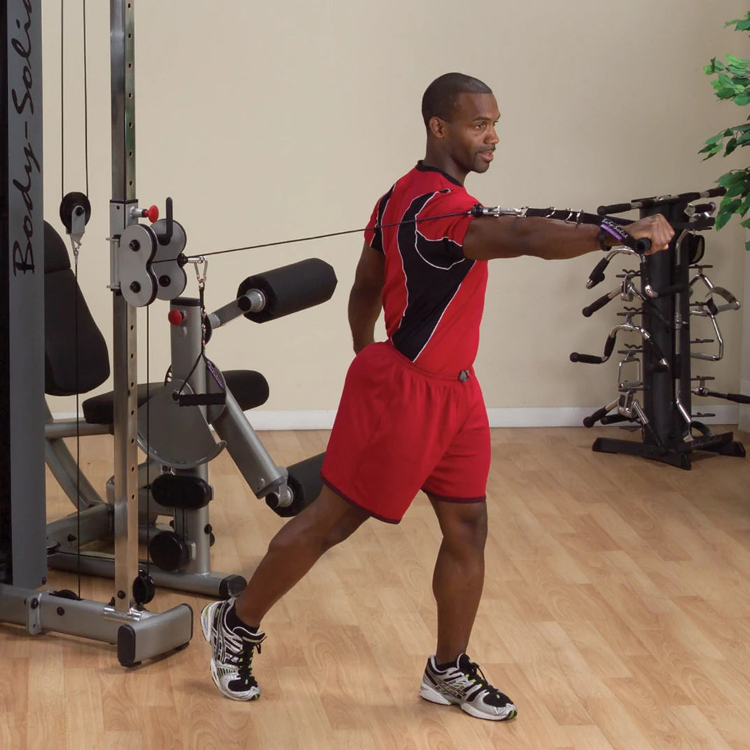 A person using the Body-Solid Pro Dual Cable Column Machine DPCCSF, performing a cable exercise with one arm extended, in a gym setting.